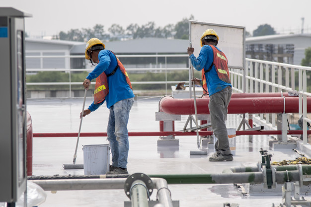 Construction worker coating epoxy paint at roof slab for water p